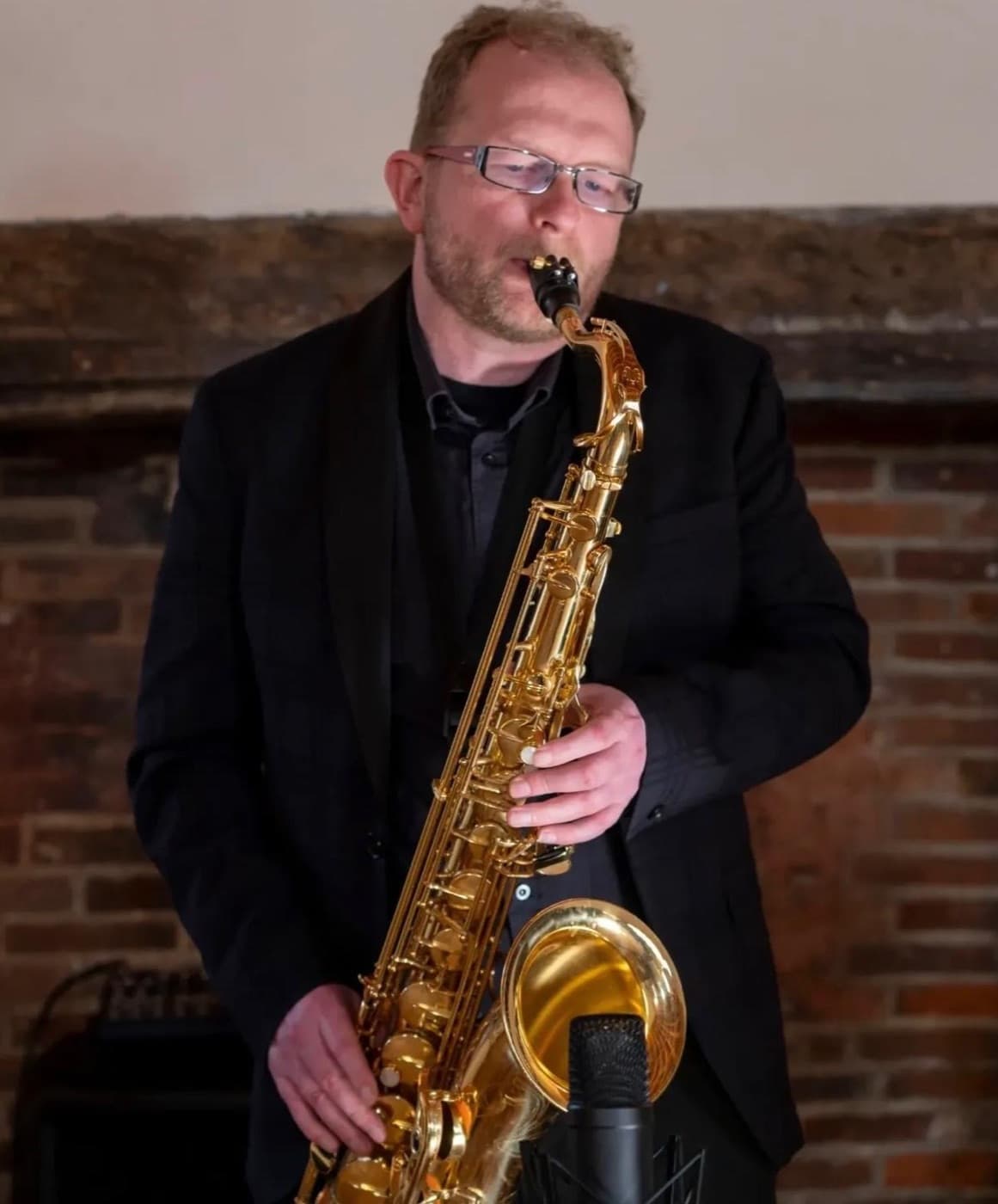 Matthew playing saxophone in front of a brick fireplace